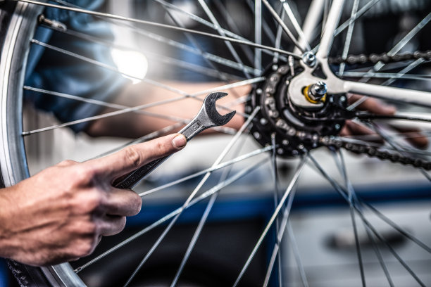 技工拿着扳手拧紧自行车轮子。图片下载