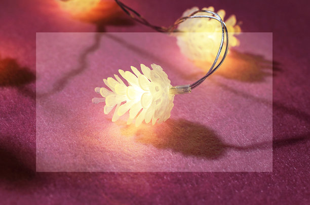 紫色背景上白色圆锥的圣诞花环。柔和的黄色光线，坚硬的阴影。选择性聚焦，侧视图，拷贝空间。图片下载