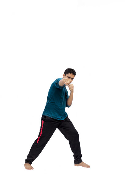 全长镜头警惕和愤怒的运动员在休闲服装摆姿势拳击手风格。男孩摆出拳姿势孤立在白色背景。图片下载