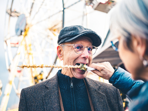 一对老年夫妇在户外圣诞市场吃零食图片下载