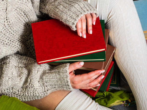 一大堆不同的旧书在女孩的手中图片下载