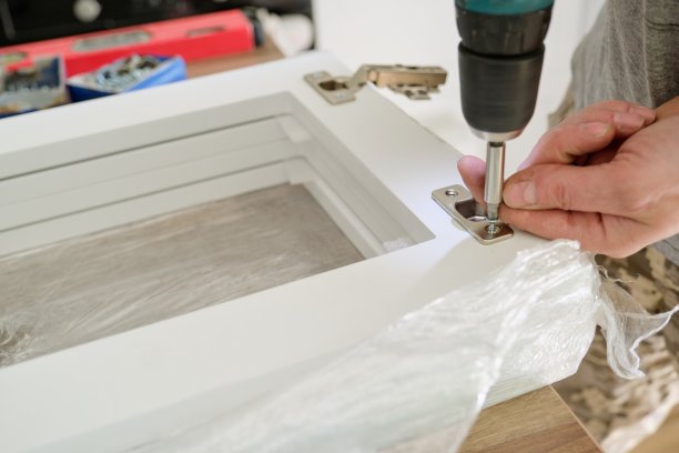 用专业工具组装家具，拧紧镀铬门铰链图片下载