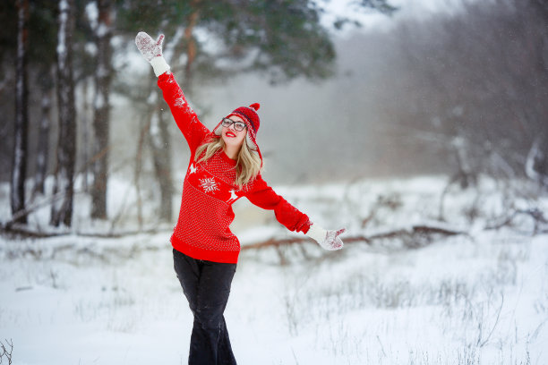 一个女人站在雪山边，戴着手套，穿着红毛衣图片下载