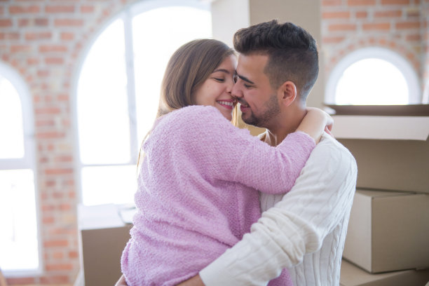 年轻美丽的夫妇拥抱在爱庆祝非常高兴搬到新公寓图片下载
