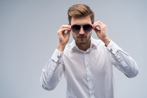 一个年轻的时尚男子的肖像戴墨镜在灰色的背景。图片下载
