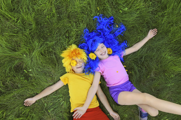 蓝色和黄色头发的孩子们的肖像躺在绿色的草地上图片下载