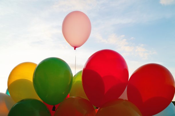 混合彩色气球在蓝天背景和阳光透过云层。蓝天上的装饰气球。29、夏天和情人概念相爱，新婚度蜜月。图片下载