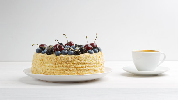 用新鲜浆果装饰的自制蛋糕和一杯咖啡放在白色的木桌上。前视图。副本的空间。图片下载