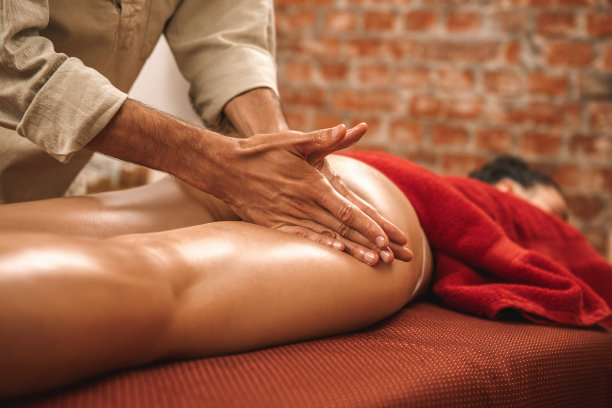 替代医学。治疗师治疗妇女做阿育吠陀按摩臀部与药草油近距离揉搓集中图片下载