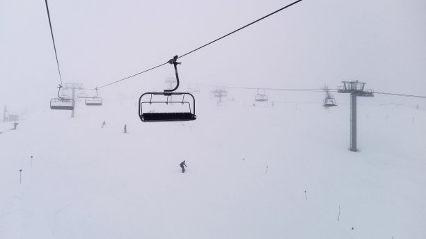 滑雪缆车在雾天和雪山中移动图片下载