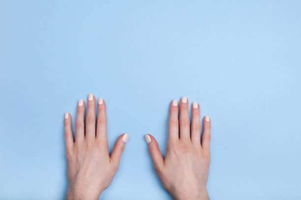 美丽的女性手与经典哑光美甲在一个蓝色的背景图片下载