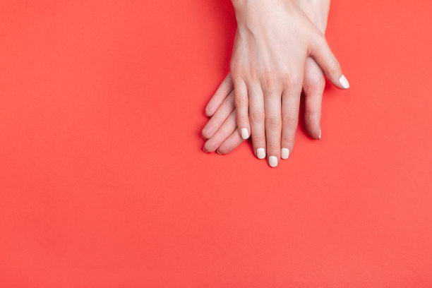 美丽的女性手与经典的哑光美甲在红色的背景图片下载