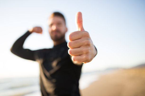 一个年轻的跑步运动员在海滩上竖起大拇指的照片。图片下载