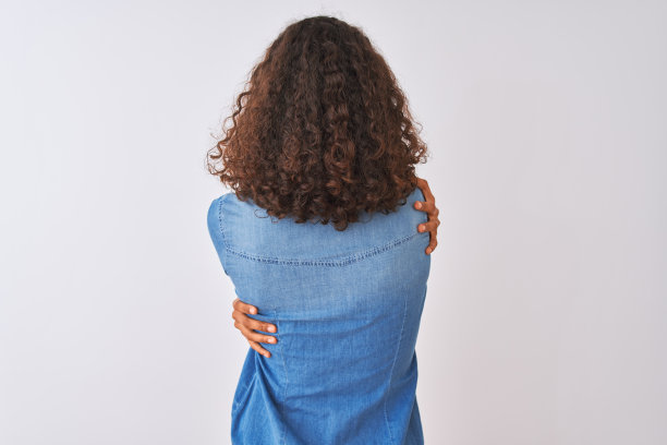 年轻的巴西女人穿着牛仔衬衫站在孤立的白色背景拥抱自己快乐和积极从背后。爱自己，关心自己图片下载