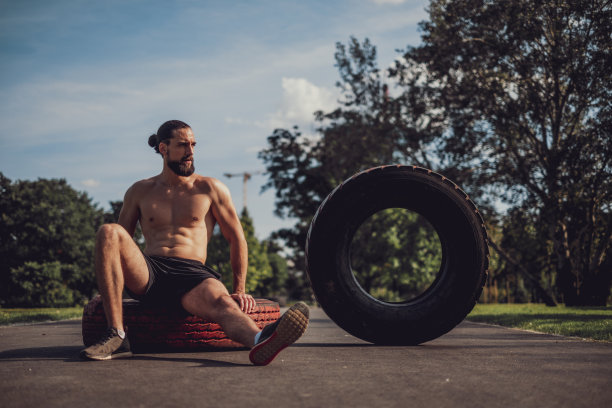 疲惫的胡子男子在锻炼后在轮胎上休息图片下载
