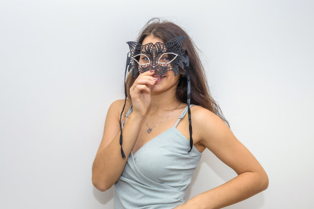 身着优雅晚礼服的女子正准备参加化妆舞会，手拿面具。新年的庆祝活动图片下载