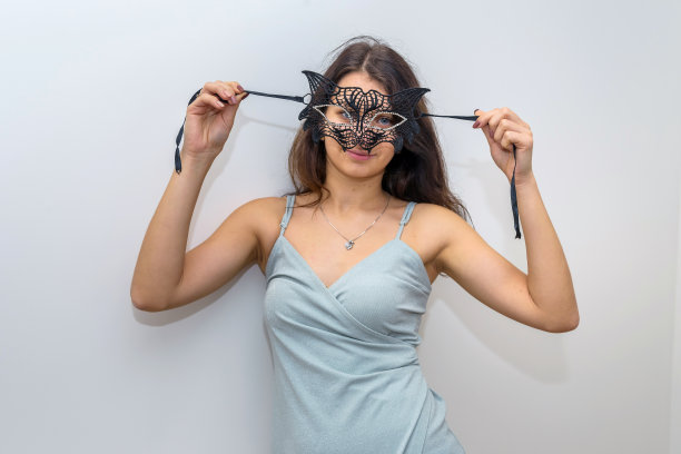 身着优雅晚礼服的女子正准备参加化妆舞会，手拿面具。新年的庆祝活动图片下载