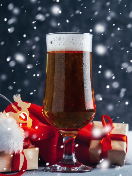 圣诞啤酒杯在圣诞老人的帽子上在黑暗的背景图片下载