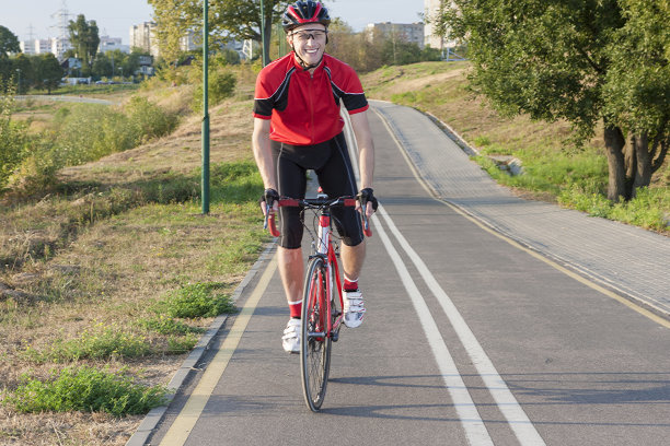 运动和自行车的想法。肖像的职业男性自行车运动员做上坡的马鞍上的公路自行车。装备齐全的专业装备。水平的形象图片下载