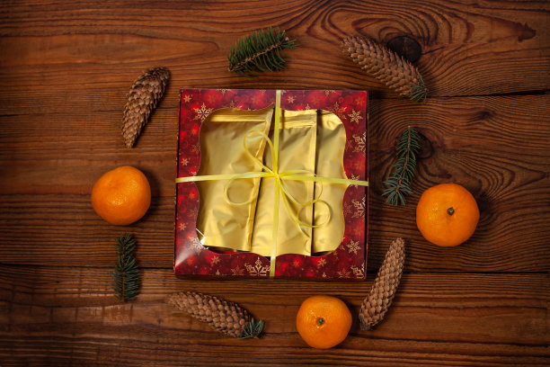 圣诞礼物装在金色的袋子里，红礼盒用新年装饰品包裹在质朴的木质背景上，平放图片下载