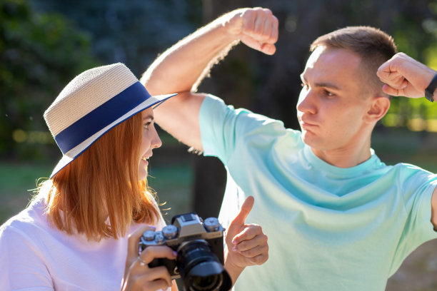 一对年轻的情侣在阳光明媚的夏日公园里拍下彼此的照片。图片下载