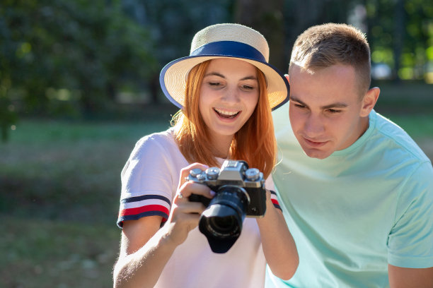 一对年轻的情侣在阳光明媚的夏日公园里拍下彼此的照片。图片下载