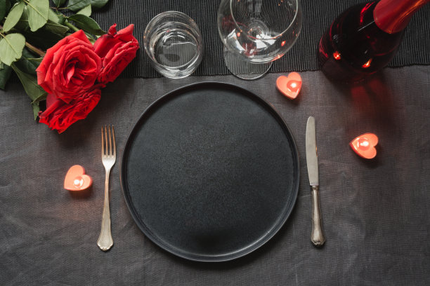 情人节或生日晚餐。典雅的餐桌，红玫瑰的黑色亚麻桌布。图片下载