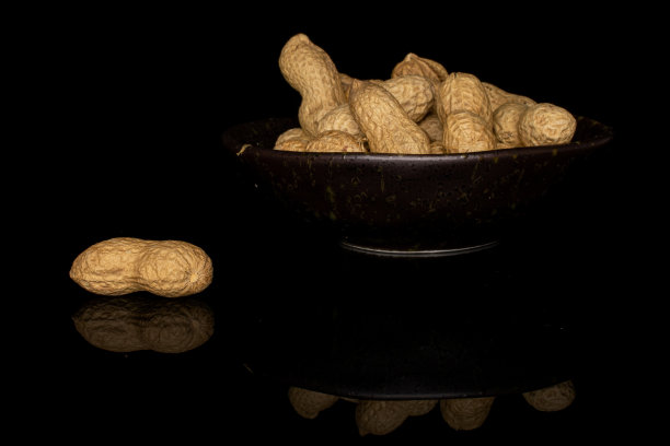 美味的米色花生隔离在黑色玻璃上图片下载