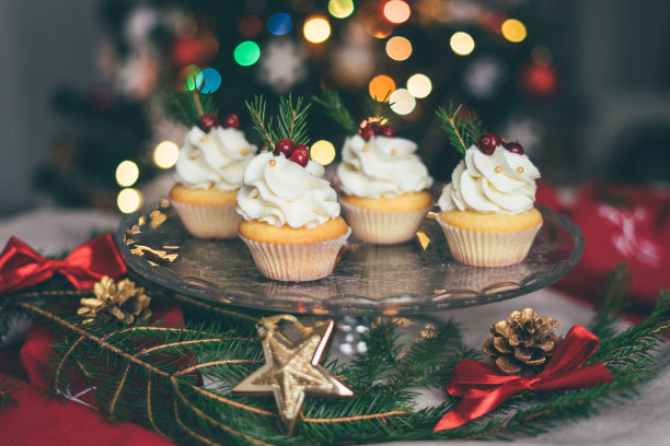 圣诞纸杯蛋糕放在盘子里，背景是圣诞树。图片下载