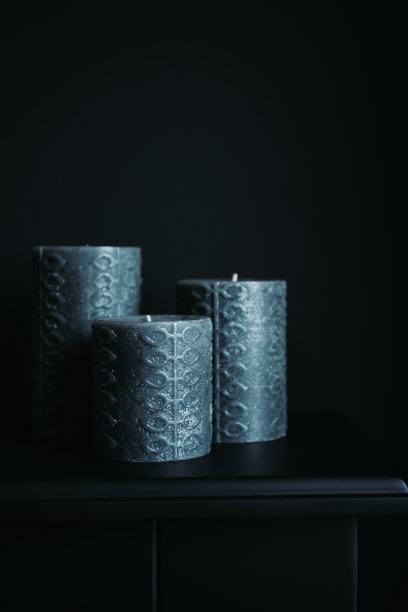 黑色墙壁上的装饰壁炉上挂着灰色的蜡烛。暗色单色房间室内风格。图片下载