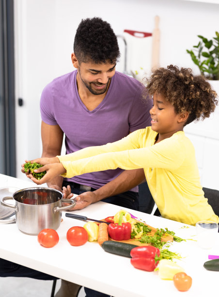 开朗的非洲男子向他可爱的女孩展示如何切蔬菜图片下载