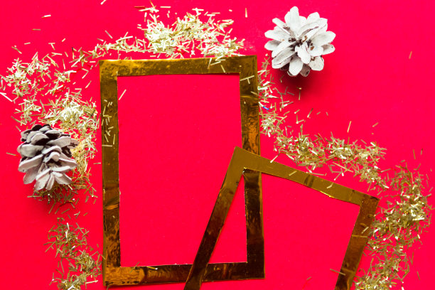 圣诞快乐，恭贺新禧。平躺照片与金色模型相框和圣诞装饰在明亮的红色背景。圣诞贺卡，横幅。为文本复制空间图片下载