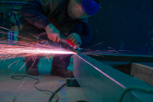 工人在工厂里用研磨机打磨金属表面。火花飞。工业的照片。图片下载