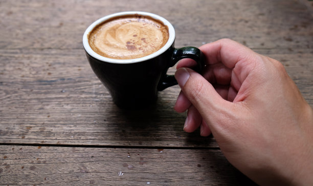 热咖啡杯放在木桌上，以花园为自然背景，清晨雨天的种植园背景——意象图片下载