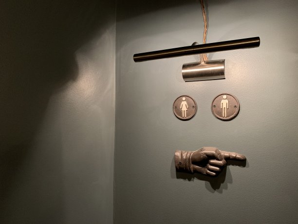 WC的标志在灰色的墙上用一只手指向右边，一盏灯照亮了东欧拉脱维亚里加酒吧的咖啡馆餐厅图片下载