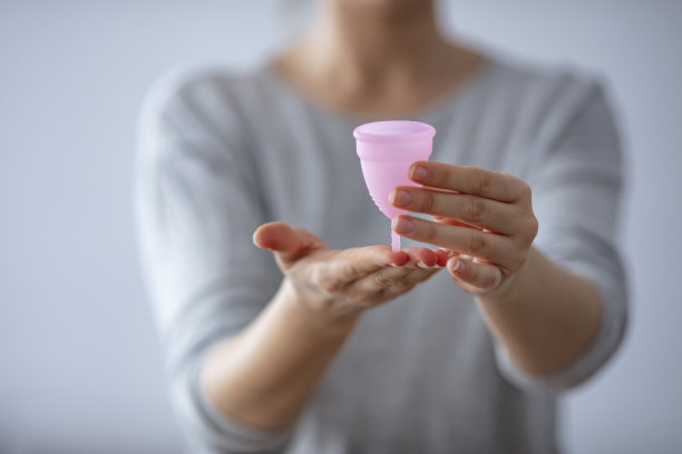 女人手拿粉红月经杯。图片下载