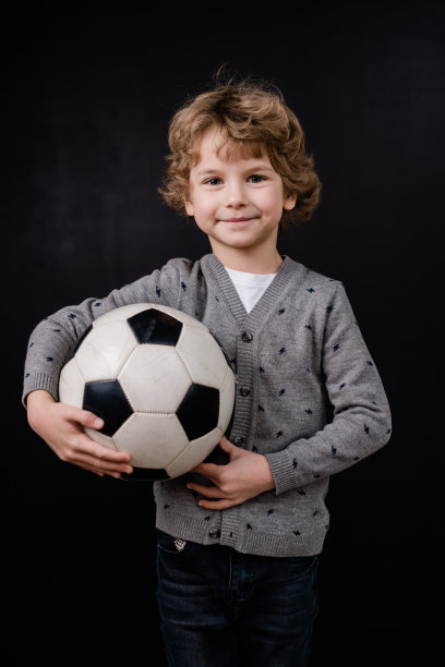 快乐的小男孩在休闲服抱着足球的胸部在隔离图片下载