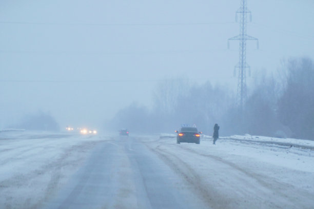那辆车在飘落的雪和雾中，晚上停在路边。图片下载