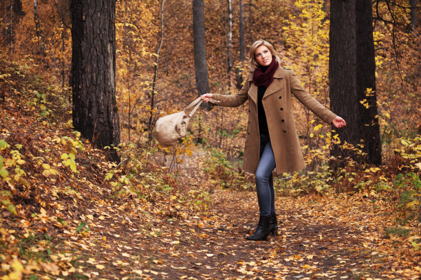 快乐的年轻时尚女人带着手提包漫步在秋天的公园图片下载