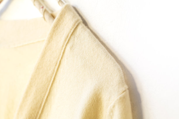 一件白色毛衣挂在衣架上，背景是白色。图片下载