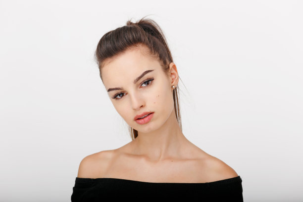 一个年轻女孩的正面肖像与马尾辫，穿着赤裸的肩膀，孤立在一个白色的背景。图片下载