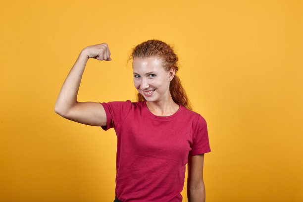 年轻，微笑的女孩做强有力的手势与右手的帮助。图片下载