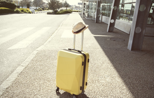 黄色行李箱和帽子在机场街头，旅游概念图片下载