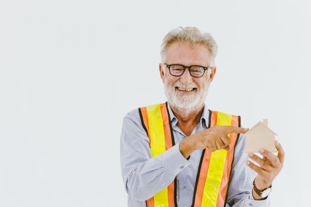 专业的长者家庭工程师建筑工人指着房子模型开心和微笑与文字的空间。图片下载