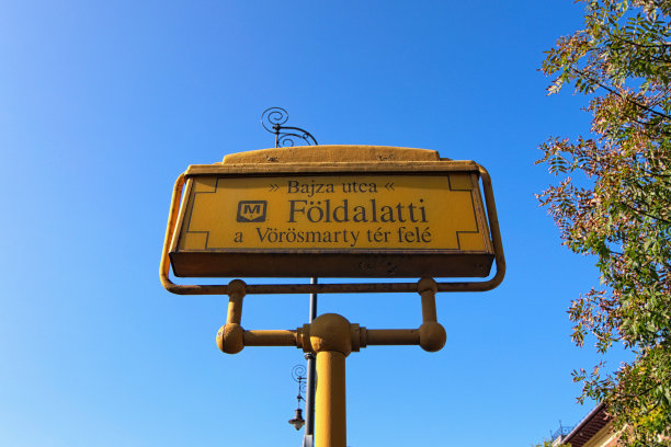 典型的布达佩斯地铁系统的街道标志。标识上写着:巴扎街，Foldalatti(地铁1号线)，通往红马蒂广场。背景是蓝色的天空。匈牙利布达佩斯图片下载