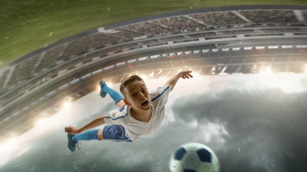 年轻男子足球运动员在体育场踢足球，背景是手电筒图片下载