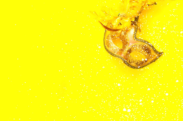 金色的狂欢节或舞台面具上的黄色背景。节日的概念。特写镜头图片下载