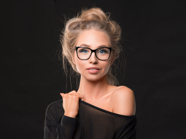 一个戴眼镜的女人的肖像。黑暗的背景。图片下载