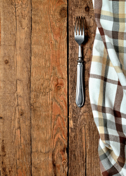 方格桌布右框架和叉子在古董木制桌子的背景-从上面看-垂直照片图片下载