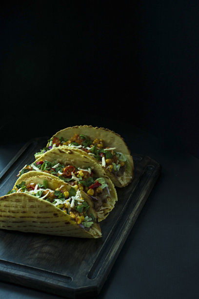 墨西哥玉米饼，肉，奶酪，玉米，洋葱和猪肉香草放在木板上的照片。番茄酱和辣椒。黑色背景。从上面的观点图片下载